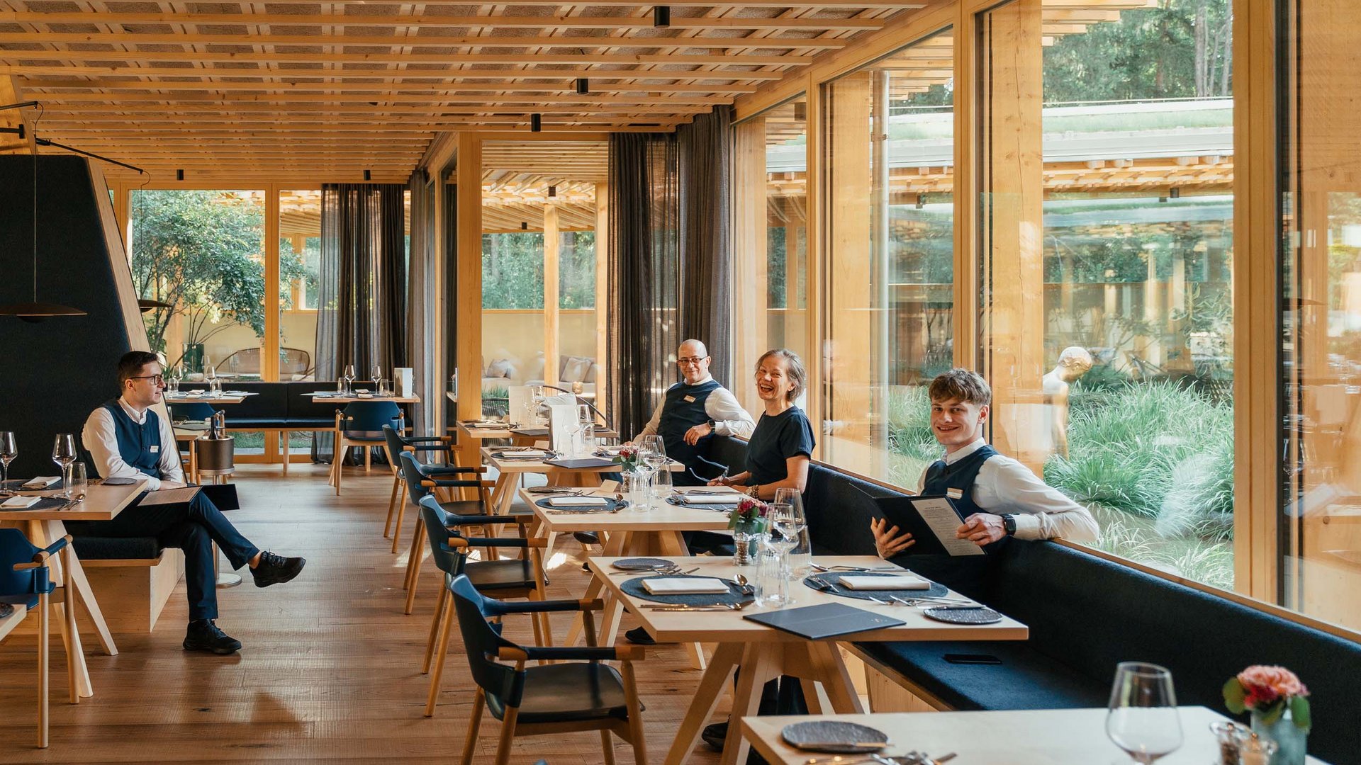 Posizioni aperte Quattro membri del personale del ristorante in un locale moderno in legno con grandi finestre