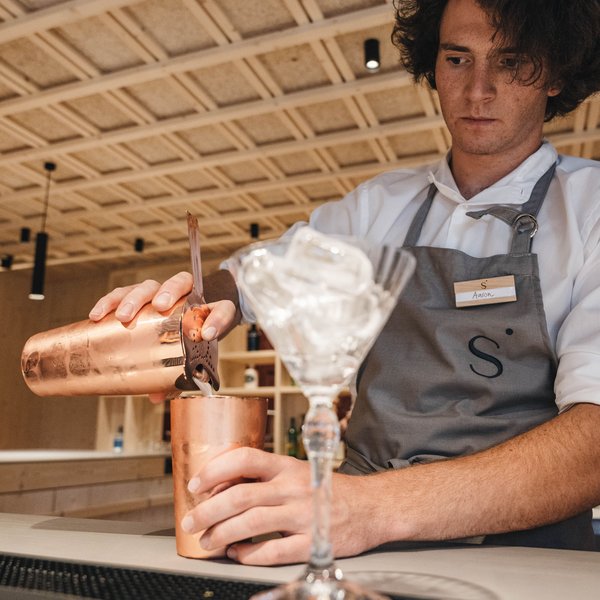 Sensoria Soulmates – Creating Memories of Bliss Bartender pouring cocktail from copper shaker into glass with ice cubes