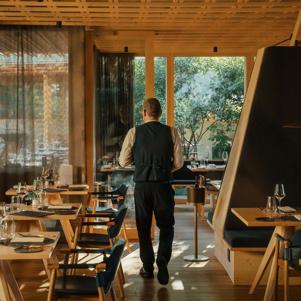 Sensoria Soulmates – Creating Memories of Bliss Waiter walking in modern restaurant with wooden furniture and large windows