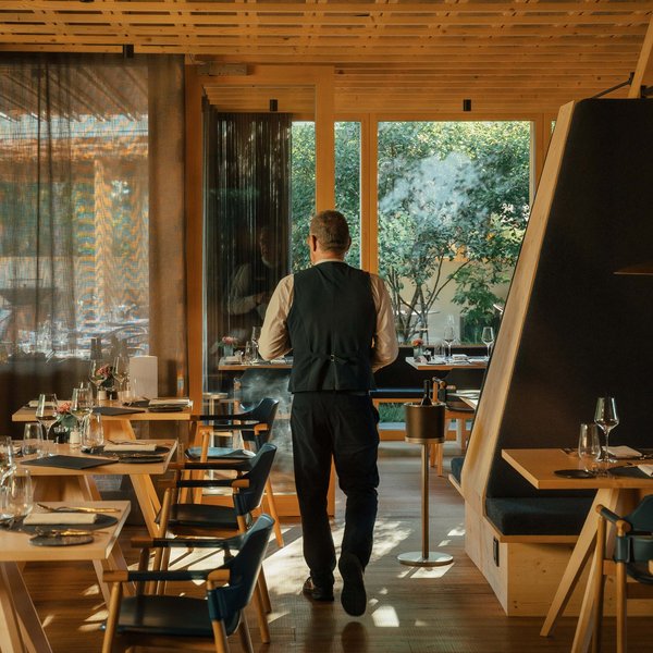 Sensoria Soulmates – Creating Memories of Bliss Kellner geht in modernem Restaurant mit Holzmöbeln und großen Fenstern