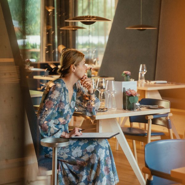 Sensoria Soulmates – Creating Memories of Bliss Woman in floral dress sitting in modern restaurant reading menu