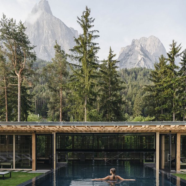 Sensoria Soulmates – Creating Memories of Bliss Woman in outdoor pool with forest, mountains, and modern wooden building in background