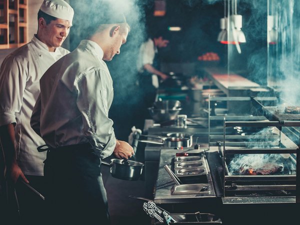 Sensoria Soulmates – Creating Memories of Bliss Two chefs cooking in a smoky restaurant kitchen at grill and stove