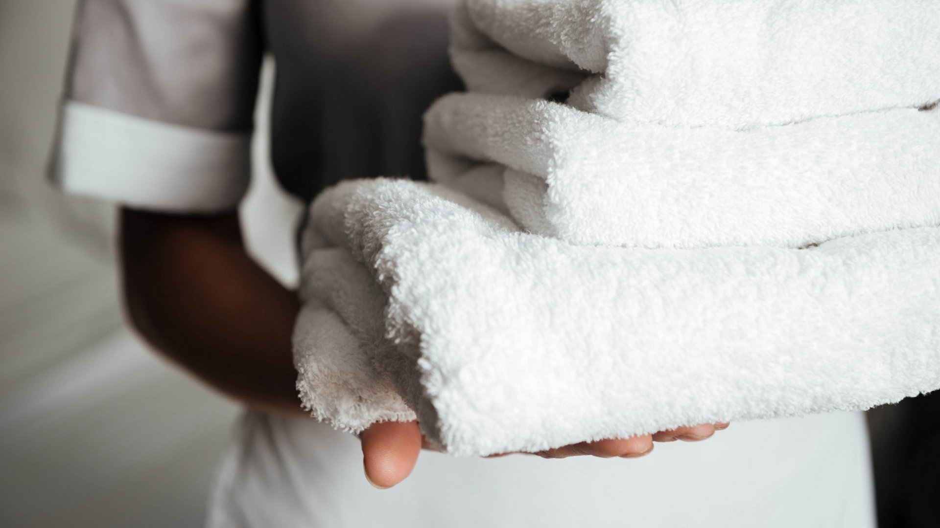 Posizioni aperte Persona che porta una pila di asciugamani bianchi