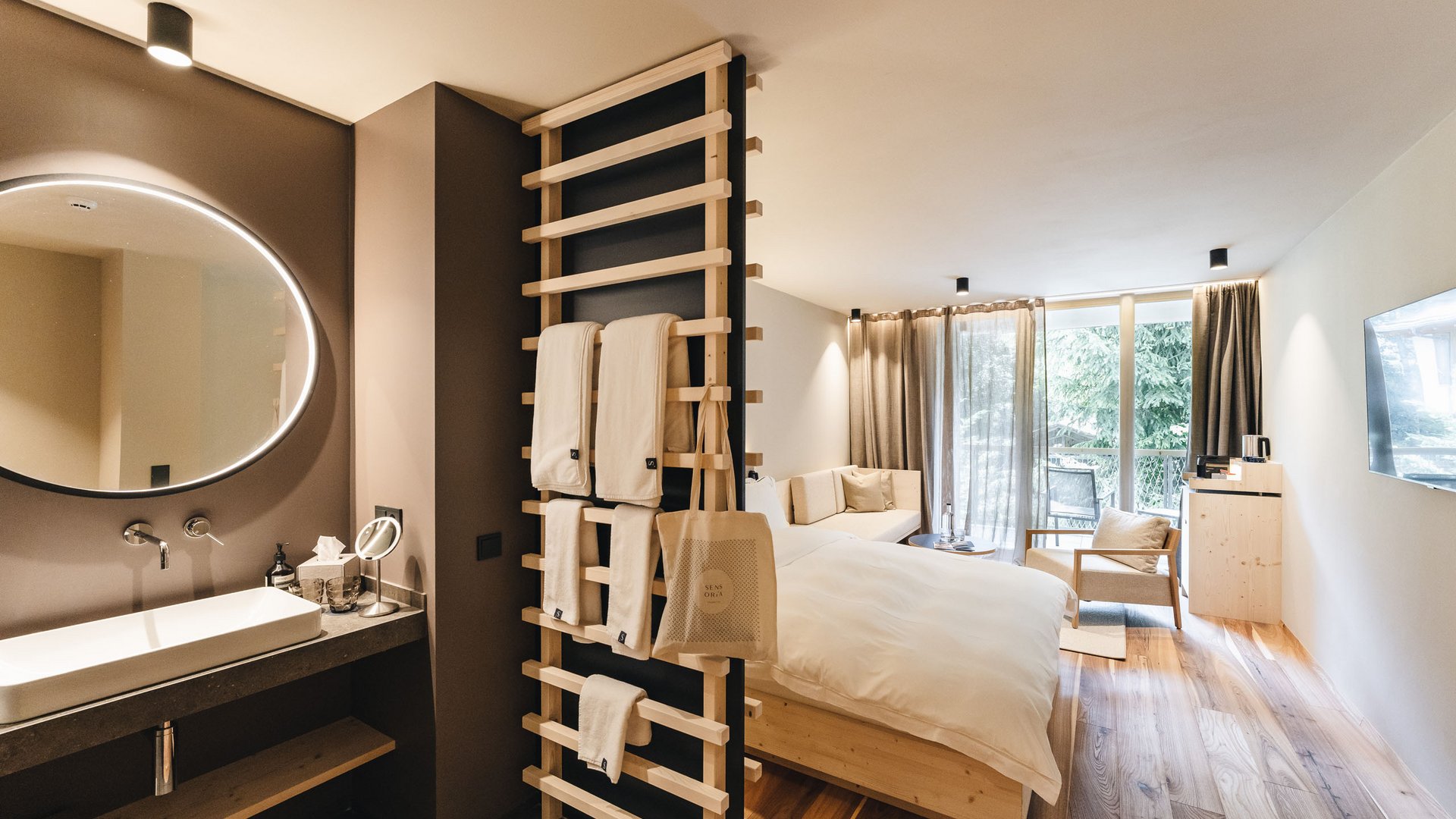 Posizioni aperte Camera d'albergo moderna con pavimento in legno, letto, divano, lavabo e grandi finestre