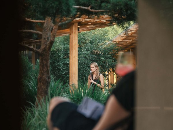 Sensoria Soulmates – Creating Memories of Bliss Woman speaking with microphone in garden, blurred person in foreground