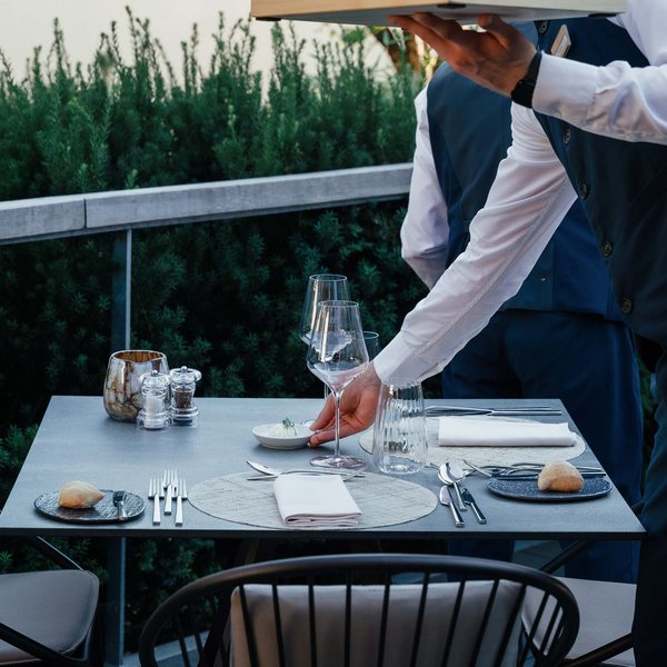 Sensoria Soulmates – Creating Memories of Bliss Waiters setting an outdoor table with glasses, cutlery, and bread