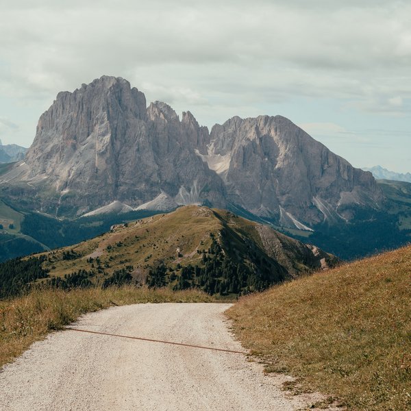 Sensoria Soulmates – Creating Memories of Bliss Gravel path leading to forested hill and rocky mountains under cloudy sky