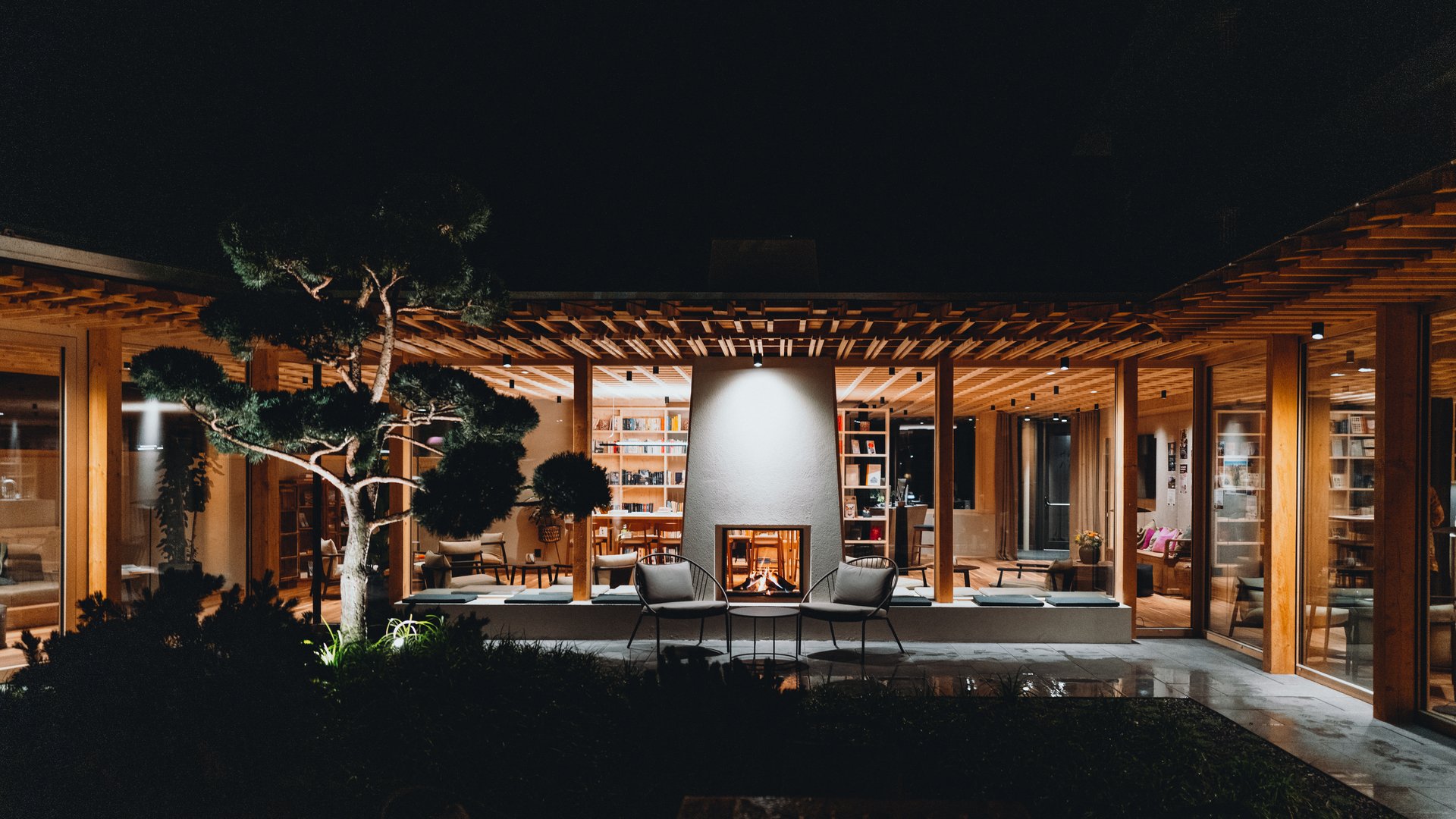 Posizioni aperte Casa moderna con cortile illuminato e camino acceso di notte