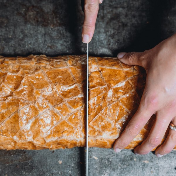 Sensoria Soulmates – Creating Memories of Bliss Hand slicing fresh baguette on dark surface