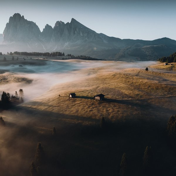 Sensoria Soulmates – Creating Memories of Bliss Morning mist over forested mountain meadow with huts and mountains in background