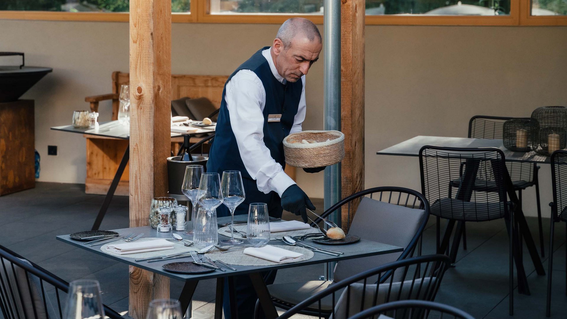 Posizioni aperte Cameriere che serve il pane a un tavolo apparecchiato in un ristorante