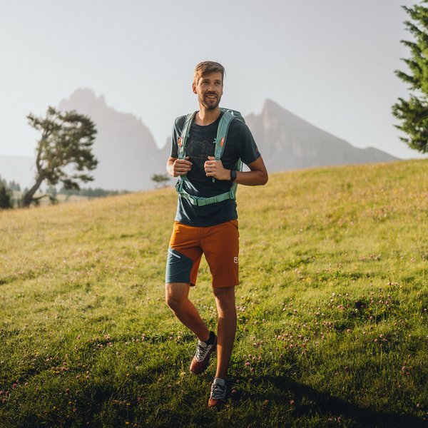Sensoria Soulmates – Creating Memories of Bliss Young man with backpack hiking on a flowering meadow in the mountains